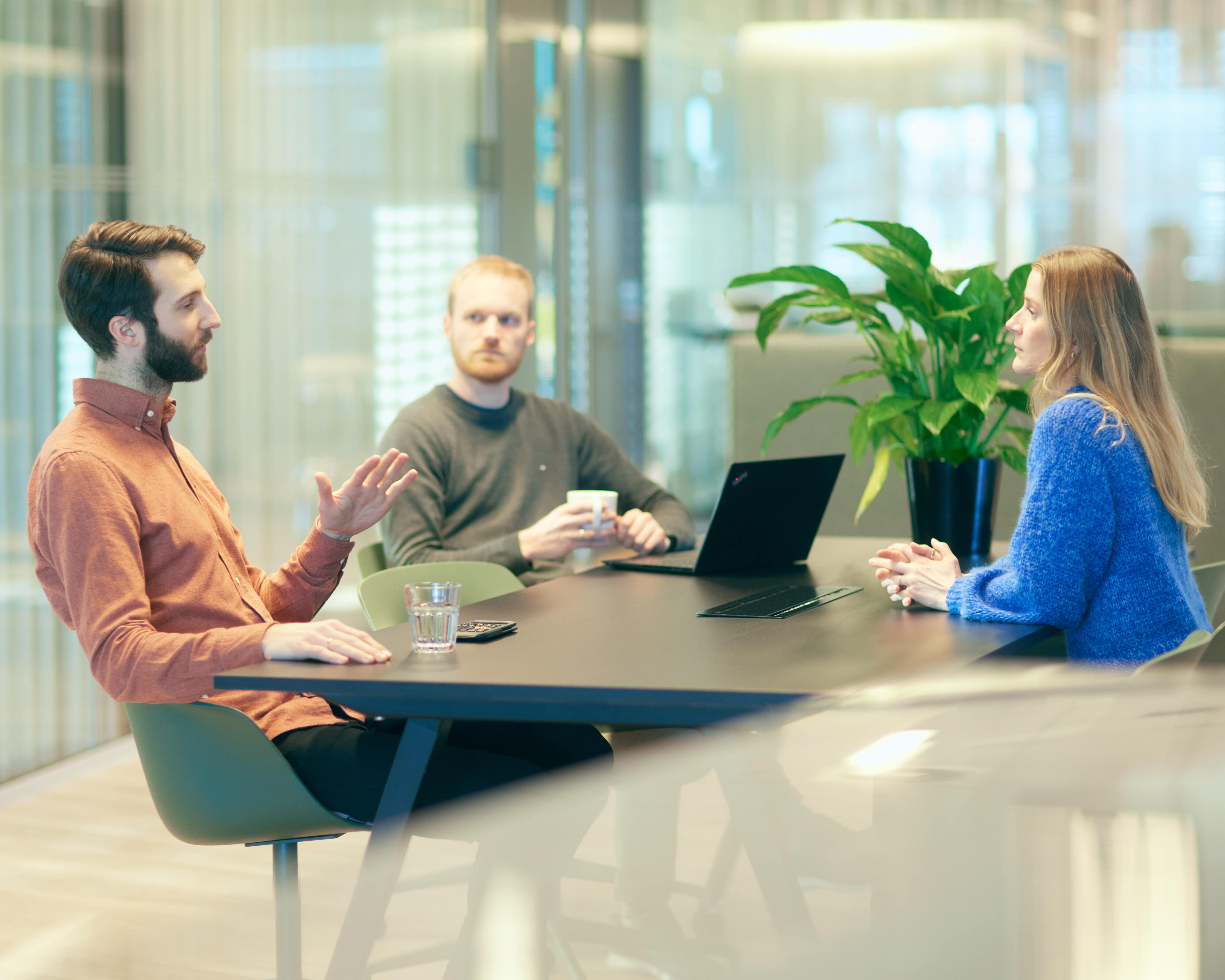 Three people discussing at a meeting table